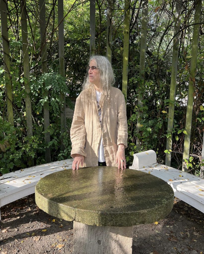 Bild von Patti Smith Besuch in Schillers magischem Garten in Jena, Deutschland im Oktober 2023. Das Bild zeigt Patti Smith hinter Schillers Tisch stehend, dabei schaut sie nach rechts.