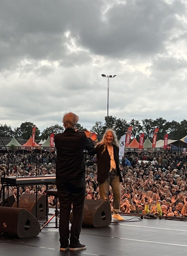 Mit Patti Smith auf Tour - Weert 2024 - von der Bühne aus macht Janine ein Bild von Tony Shanahan, der ein Bild von Patti Smith macht. Im Hintergrund das applaudierende Publikum des Bospop Festivals