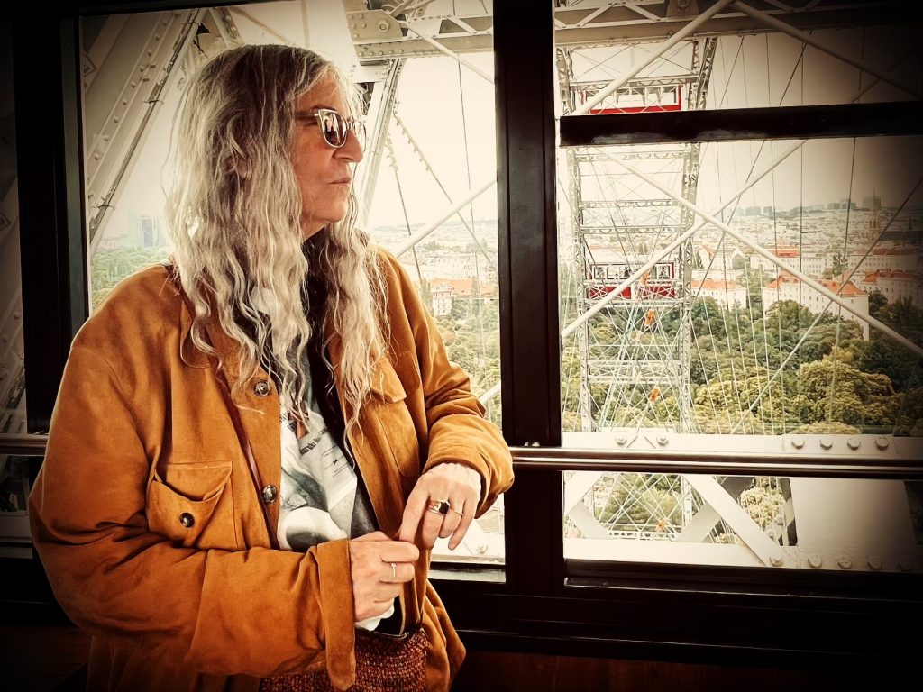 Patti Smith im Juli 2024. Sie steht im Riesenrad im Prater in Wien und schaut aus dem Fenster einer Gondel.