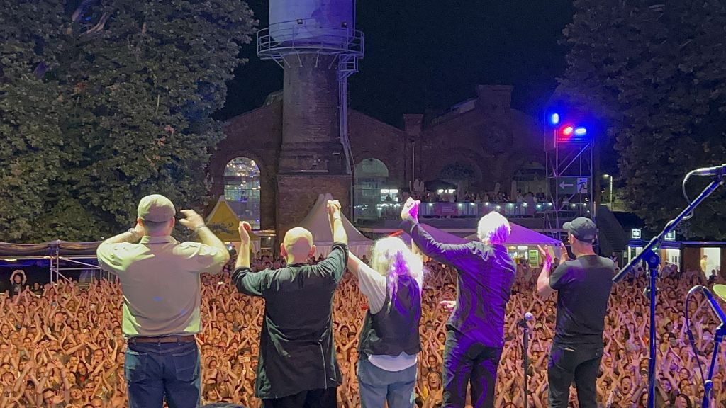 Patti Smith und ihr Quartett stehen nach ihrem letzten Song nebeneinander auf der Bühne, halten sich an den Händen kurz vor ihrer Verbeugung vor dem Publikum am METAStadt Open Air in Wien.