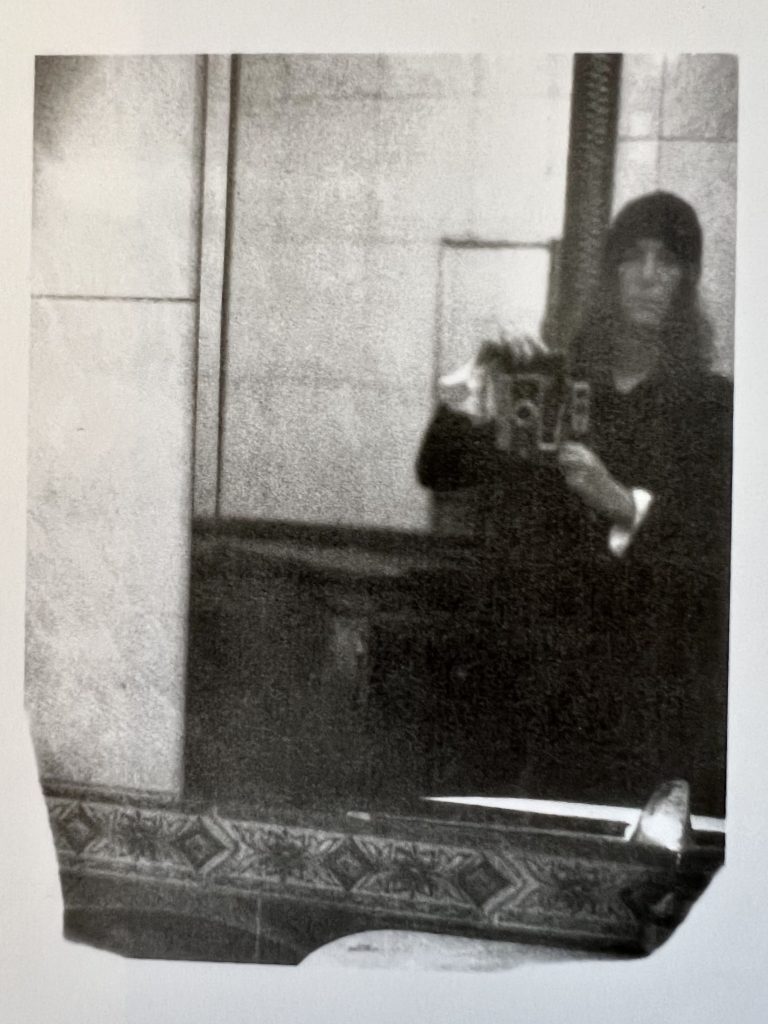 Bild des Polaroids von Patti Smith aufgenommen, zeigt ein Spiegelbild von Patti Smith mit ihrer Polaroid Land 250.
