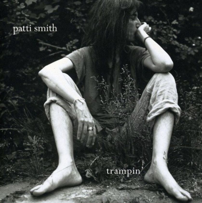 Das Bild zeigt Patti Smith Albumcover Trampin auf der Patti Smith am Boden sitzend in schwarz/weiß.
