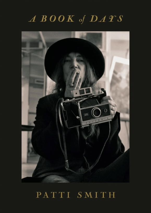 Patti Smith Buchcover A Book Of Days zeigt Patti Smith frontal mit Hut und ihre Polaroid haltend.