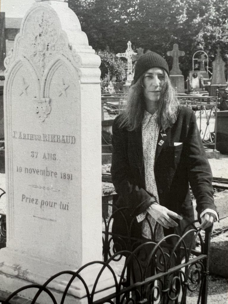 Patti Smith steht neben dem Grabstein von Arthur Rimbaud. Dieses Foto in schwarz/weiß wurde für die Erinnerungskarte anlässlich der Ausstellungseröffnung von EVIDENCE im Centre Pompidou in Paris am 20. Oktober 2022 verwendet.