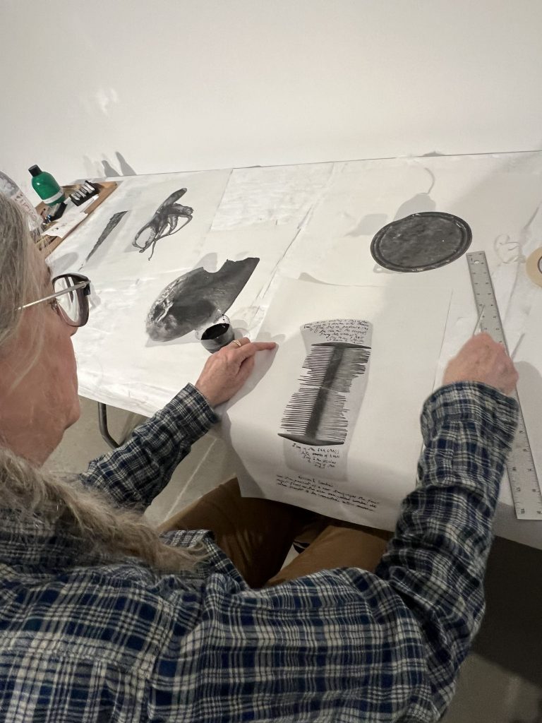 Patti Smith und Soundwalk Collective bereiten die Ausstellung CORRESPONDENCES in der Gallery in New York City vor. Das Bild zeigt Patti Smith in blau kariertem Hemd ein Exponat gestaltet.