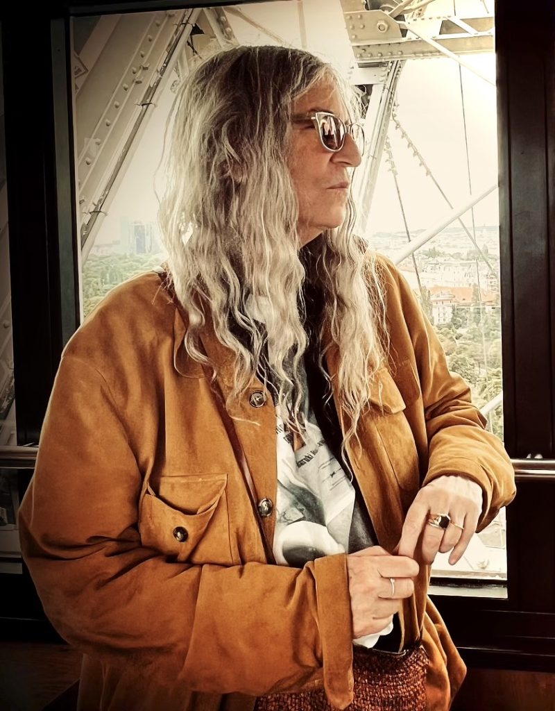 Patti Smith im Juli 2024. Sie steht im Riesenrad im Prater in Wien und schaut aus dem Fenster einer Gondel.