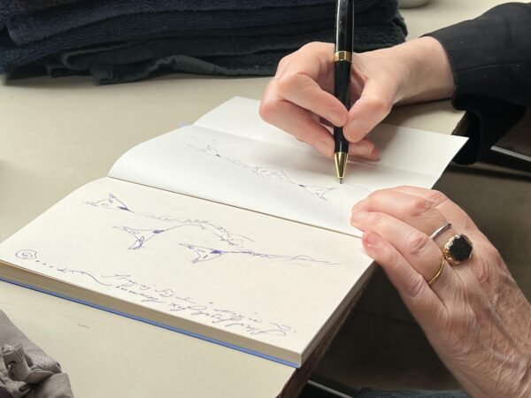 Patti Smith fertigt Handzeichnungen des "floral fugal fox blooming" und des "fugal fox compass“ im aufgeschlagenen Buch.