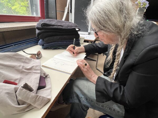 Patti Smith fertigt Handzeichnungen des "floral fugal fox blooming" und des "fugal fox compass“ im aufgeschlagenen Buch.
